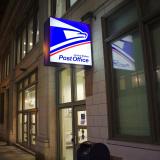 The USPS sign lit up at night